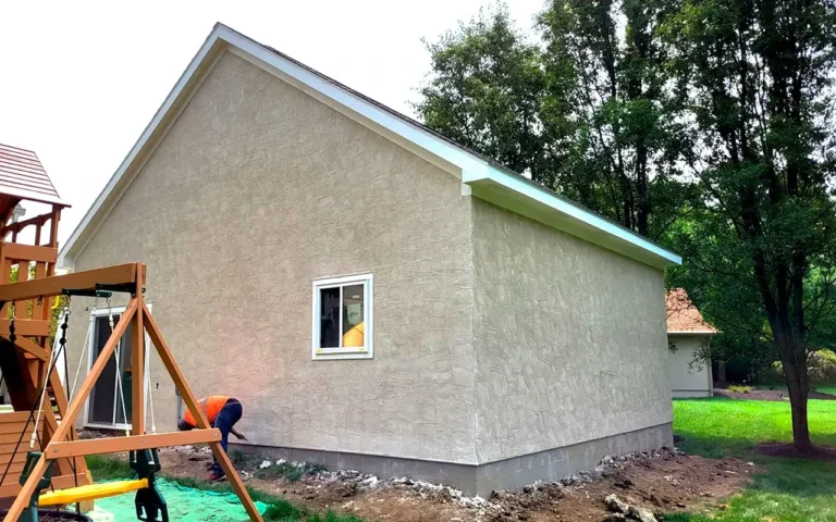 Professional plasterer applying full stucco finish to a garden shed